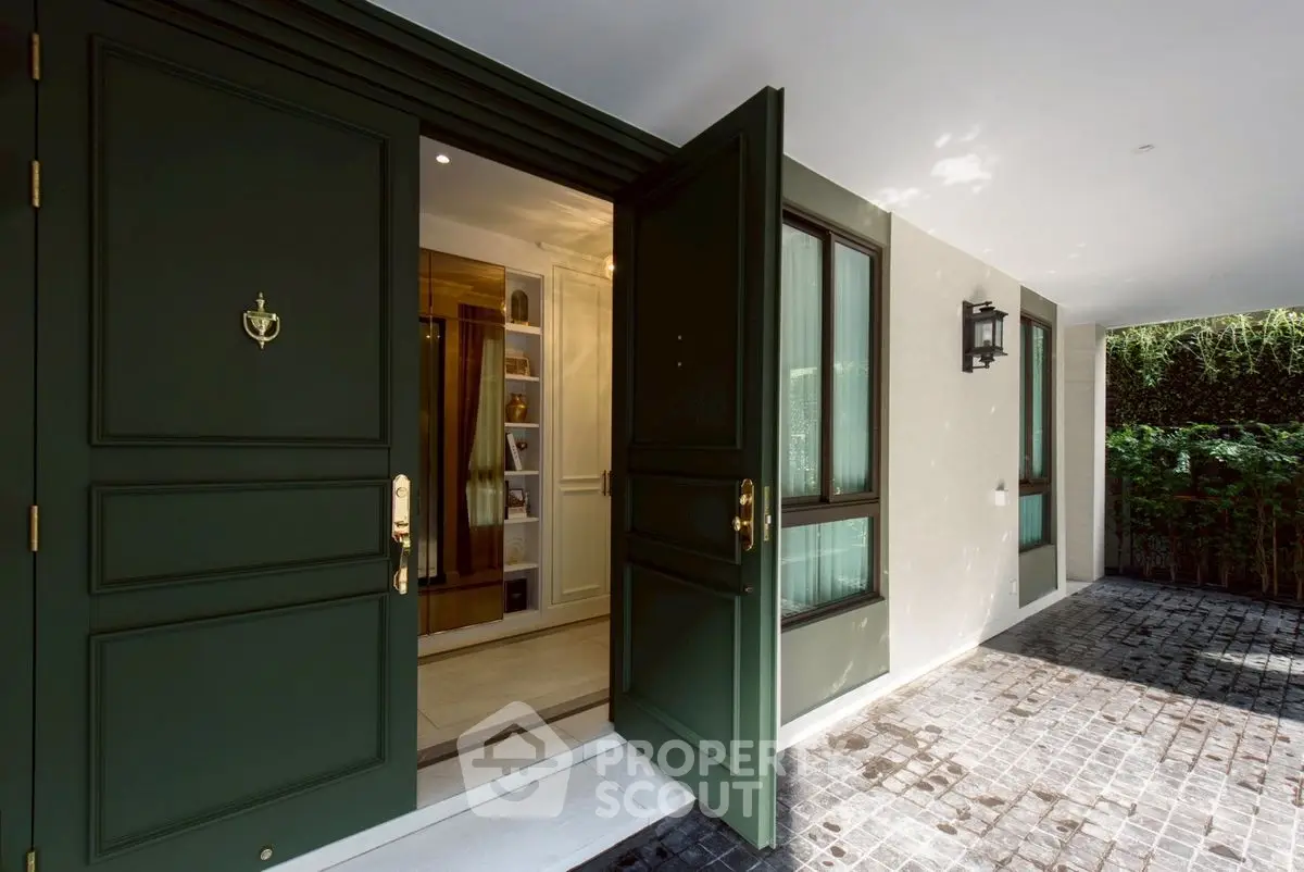 Elegant entrance with open green doors leading to a luxurious interior, showcasing modern design.