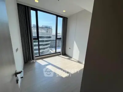 Bright room with large window offering city view, ideal for modern living.