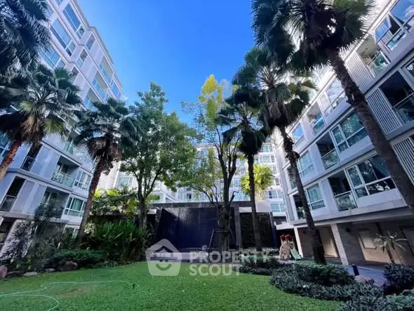 Modern apartment building with lush garden and tall palm trees