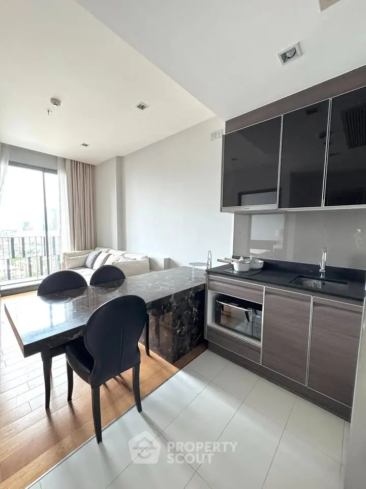 Modern open-layout kitchen with sleek cabinets and dining area in a bright apartment.