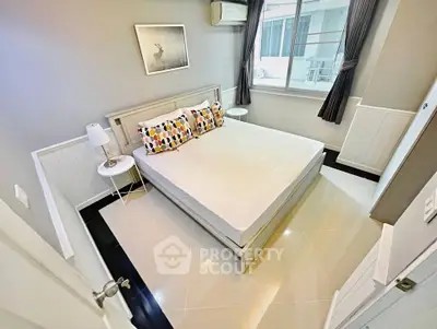 Modern bedroom with stylish decor and large window in a cozy apartment.