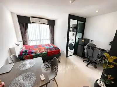 Modern studio apartment with colorful bedding, compact workspace, and dining area, featuring natural light and sleek design.