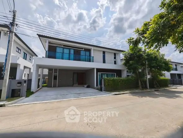 Modern two-story house with spacious driveway and lush greenery