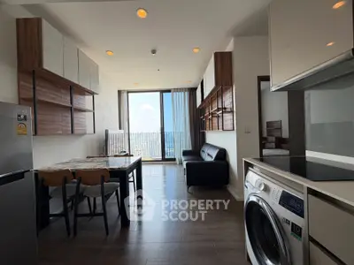 Modern open-plan living room with dining area and washing machine, featuring sleek furniture and city view.