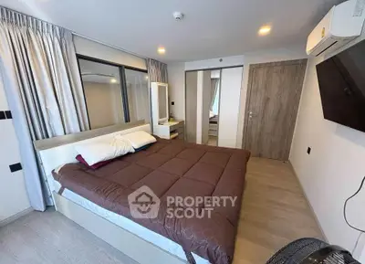 Modern bedroom with cozy bedding and wall-mounted TV in stylish apartment.