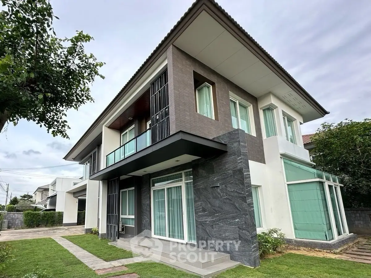 Modern two-story house with large windows and landscaped garden