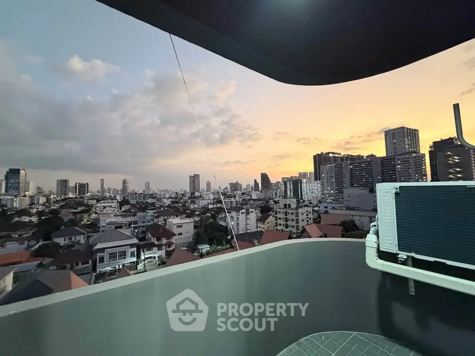 Stunning cityscape view from a modern balcony at sunset, showcasing urban skyline and vibrant sky.