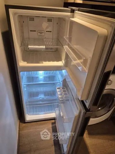 Modern kitchen with open fridge and washing machine, showcasing sleek appliances and ample storage space.