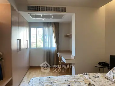 Cozy bedroom with built-in wardrobe and study desk, featuring natural light and modern design.
