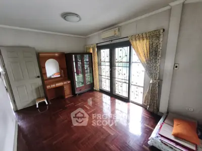 Spacious bedroom with wooden flooring and large windows for natural light