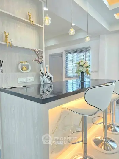 Modern kitchen with sleek bar counter and stylish stools, featuring elegant decor and ambient lighting.