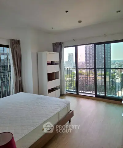 Spacious bedroom with large windows offering stunning city views in a modern apartment.
