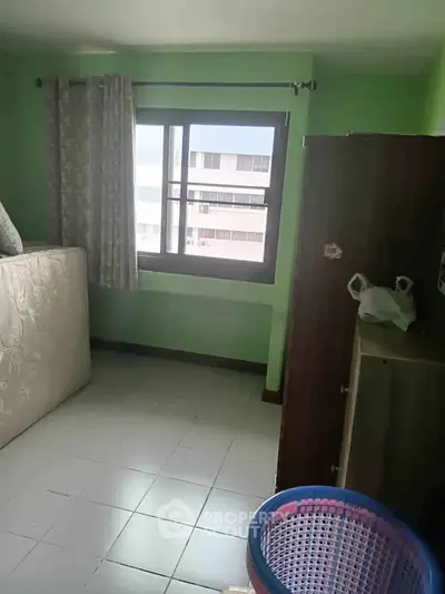 Cozy bedroom with green walls and large window offering natural light.
