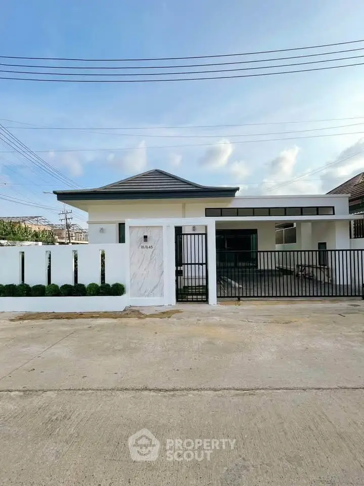 Modern single-story house with sleek design and gated entrance in a serene neighborhood.