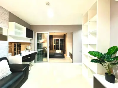 Modern living room with sleek design, featuring a cozy bedroom view through glass doors, perfect for urban living.
