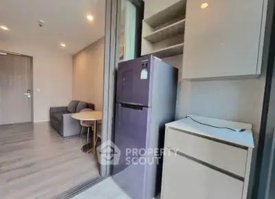 Modern apartment interior with sleek kitchen and cozy living area, featuring a stylish fridge and contemporary furniture.