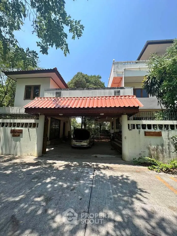 Charming two-story house with carport and lush greenery in a serene neighborhood.