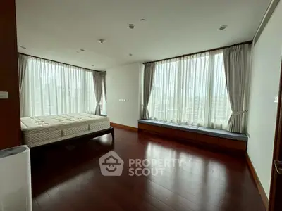 Spacious bedroom with large windows and wooden flooring, perfect for natural light lovers.