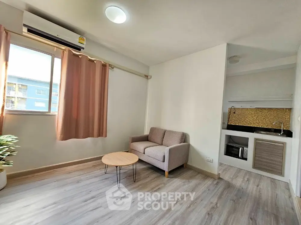 Modern living room with cozy sofa and kitchenette in open layout apartment.