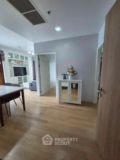 Spacious entryway leading to a modern living room with stylish decor and wooden flooring.