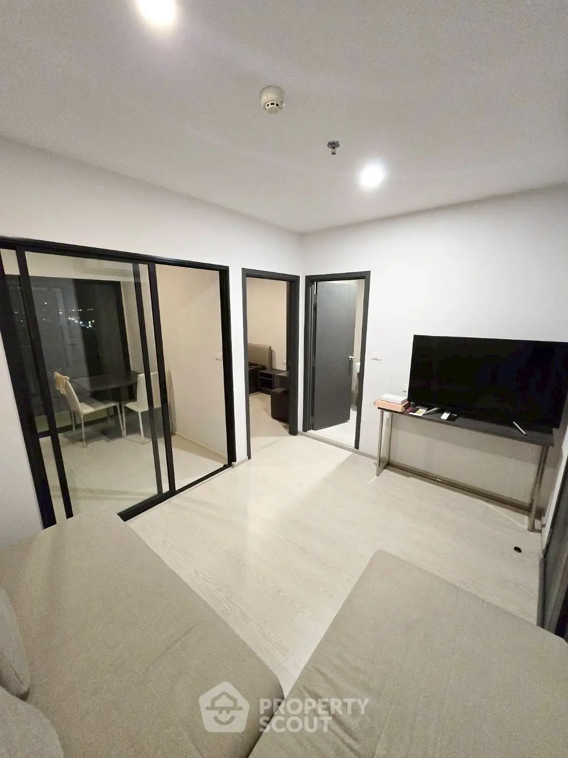 Modern living room with sleek design and glass doors leading to a cozy study area.