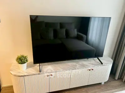 Modern living room with sleek TV on stylish console and cozy sofa, perfect for relaxation.