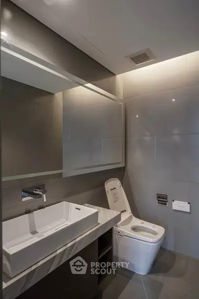Modern bathroom with sleek fixtures and elegant design, featuring a stylish sink and contemporary toilet.