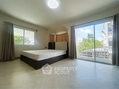 Spacious bedroom with large windows and balcony access in modern apartment