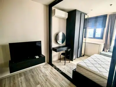 Modern bedroom with stylish decor, featuring a large mirror, TV, and natural light from a window.