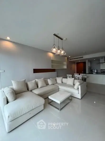 Spacious modern living room with elegant white sectional sofa and open kitchen layout.