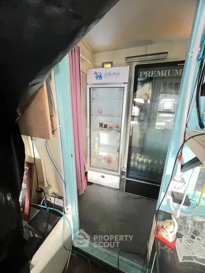 Compact storage area with refrigerators and minimal decor, ideal for small business or cafe setup.