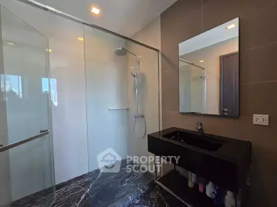 Modern bathroom with sleek black sink and spacious glass shower enclosure.