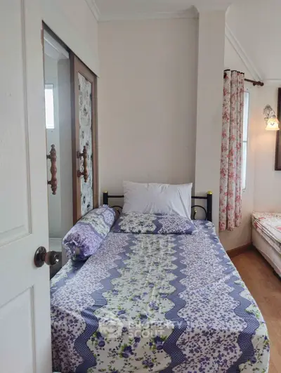 Cozy bedroom with floral bedding and curtains, classic wooden door, and a warm, inviting atmosphere perfect for relaxation.