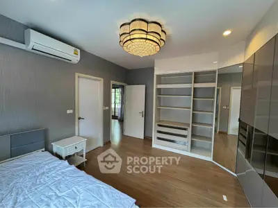 Spacious bedroom with modern chandelier and built-in storage in a stylish apartment.