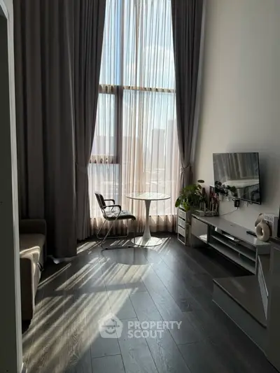 Modern living room with high ceilings, large window, and stylish decor in urban apartment.