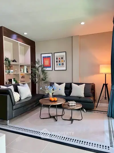 Stylish modern living room with black sofas, chic decor, and ambient lighting.