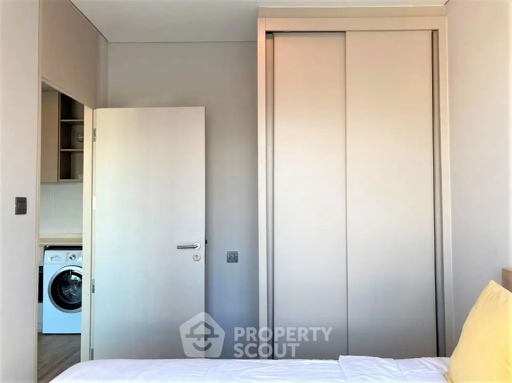 Modern bedroom with built-in wardrobe and washing machine view