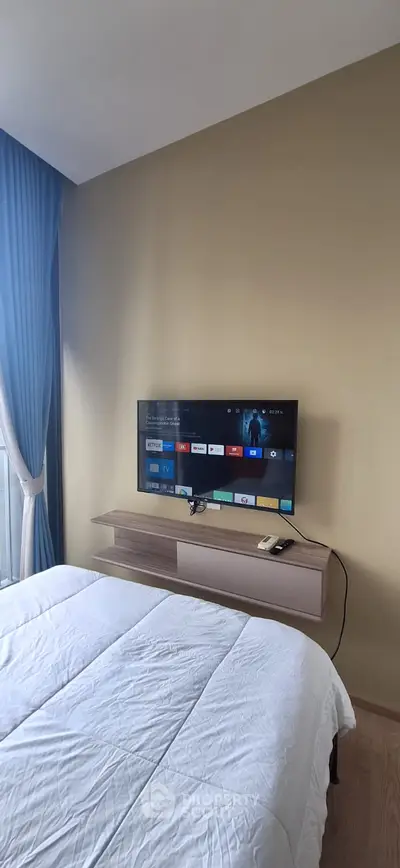 Modern bedroom with wall-mounted TV and elegant blue curtains