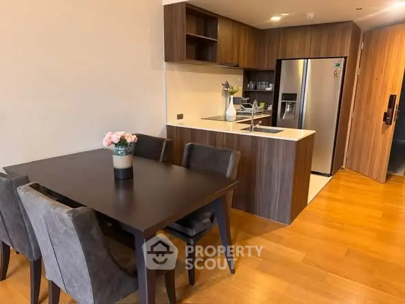 Modern kitchen with dining area, sleek wooden cabinets, and stainless steel appliances.