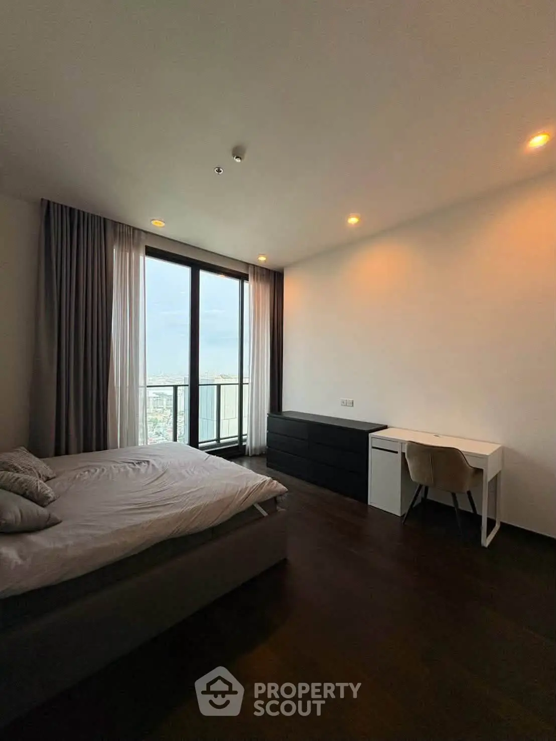 Spacious bedroom with city view, featuring modern furniture and large windows for natural light.