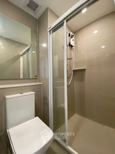 Modern bathroom with sleek shower and toilet in contemporary apartment.