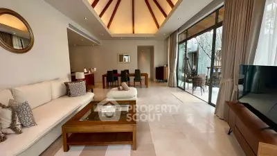 Luxurious living room with high ceiling and elegant decor, featuring a spacious seating area and large windows.