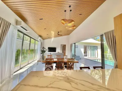 Luxurious open-plan living room with pool view and elegant wooden ceiling design.