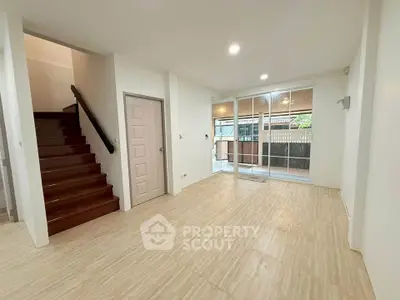 Spacious modern living room with wooden staircase and large windows for natural light.