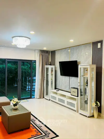 Elegant living room with modern decor, large TV, and garden view through sliding glass doors.
