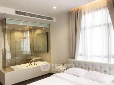 Luxurious bedroom with glass-enclosed bathtub and elegant decor