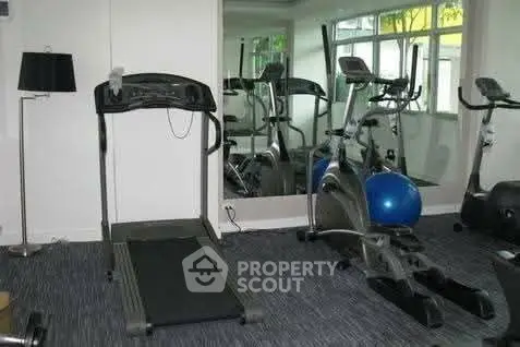 Modern home gym with treadmill and exercise bike in bright room