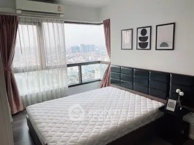 Modern bedroom with city view, featuring large windows and stylish decor.