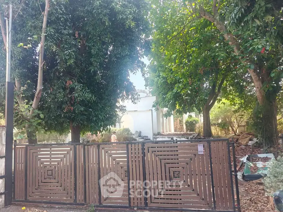 Charming property with lush greenery and stylish wooden gate, offering privacy and tranquility.