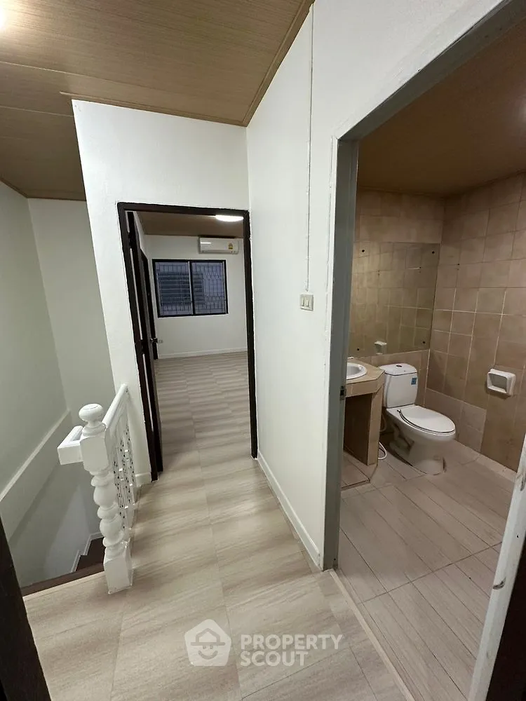 Spacious hallway leading to a modern bathroom and bedroom with sleek flooring.